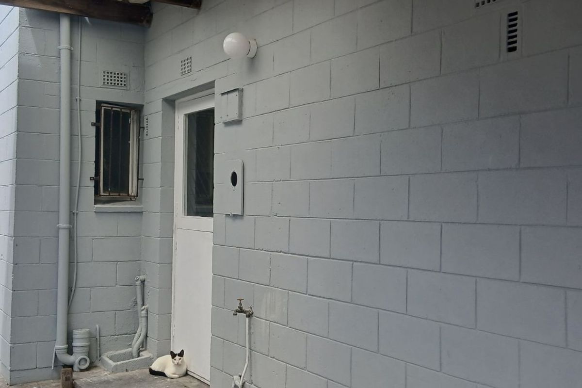 A side exterior view of the property featuring painted concrete block walls, a utility door, and external plumbing fixtures.