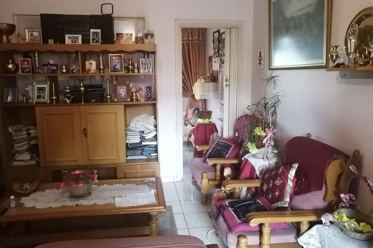 A living room featuring tiled flooring and a doorway leading to an adjacent room, providing a functional and traditional living space.