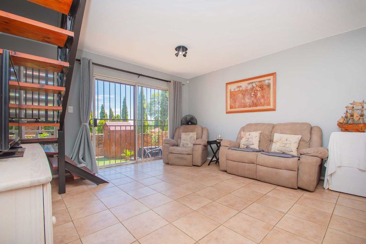 A living room featuring tiled flooring, a staircase with wooden treads, and sliding glass doors with security bars leading to the exterior.