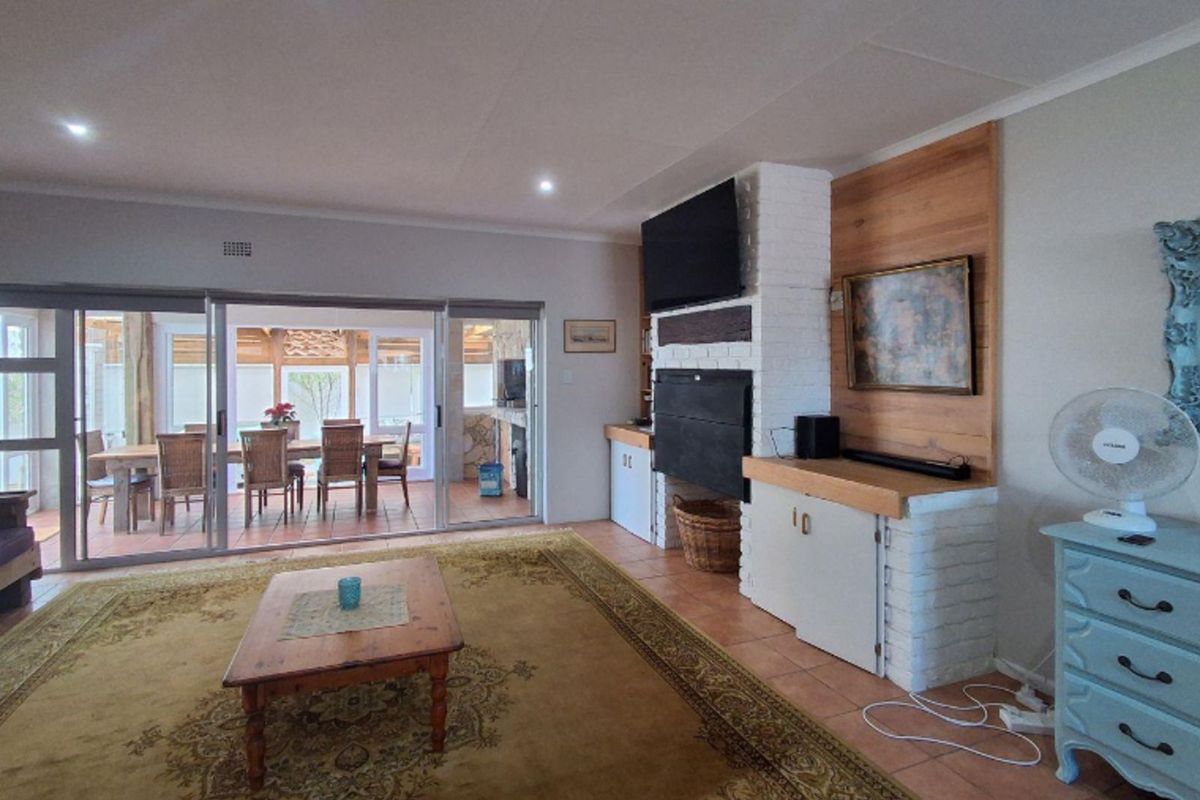 Spacious living room featuring a built-in brick fireplace with wood paneling and large sliding glass doors opening onto a covered patio area.
