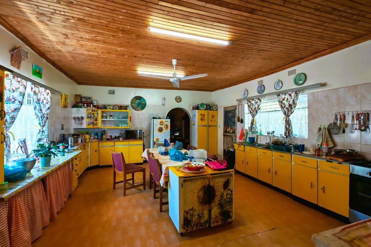 Spacious farmhouse kitchen featuring extensive yellow cabinetry, tiled splashbacks, and a timber-clad ceiling, offering a traditional rustic aesthetic with ample storage and workspace.