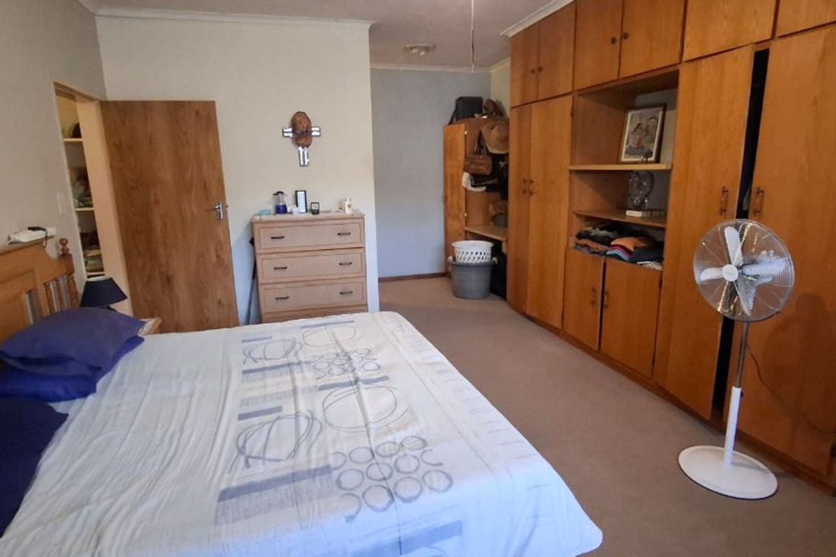 A spacious bedroom featuring extensive built-in wooden cabinetry and carpeted flooring, offering ample storage space.