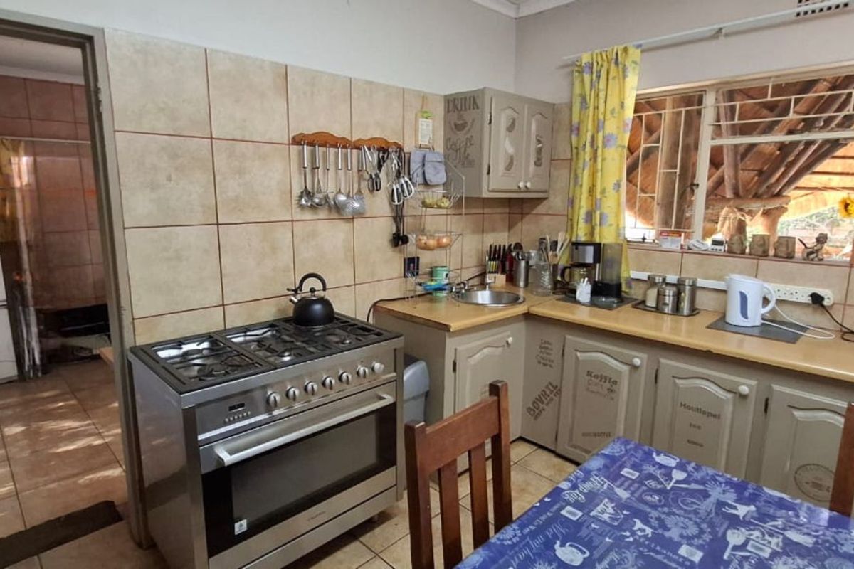 A functional kitchen featuring a stainless steel gas stove, tiled splashbacks, and built-in cabinetry, with an adjacent utility area visible.