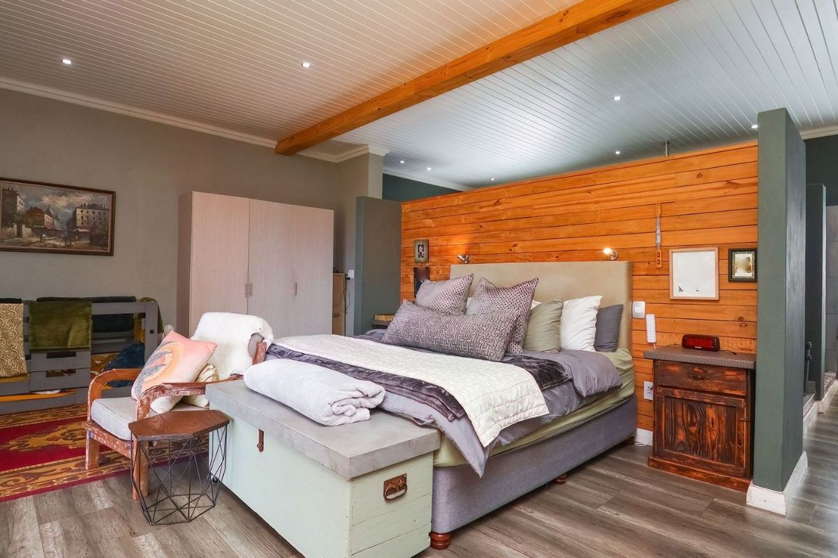 Spacious bedroom featuring a timber-clad feature wall, recessed downlighting, and wood-look flooring, creating a warm and inviting atmosphere.