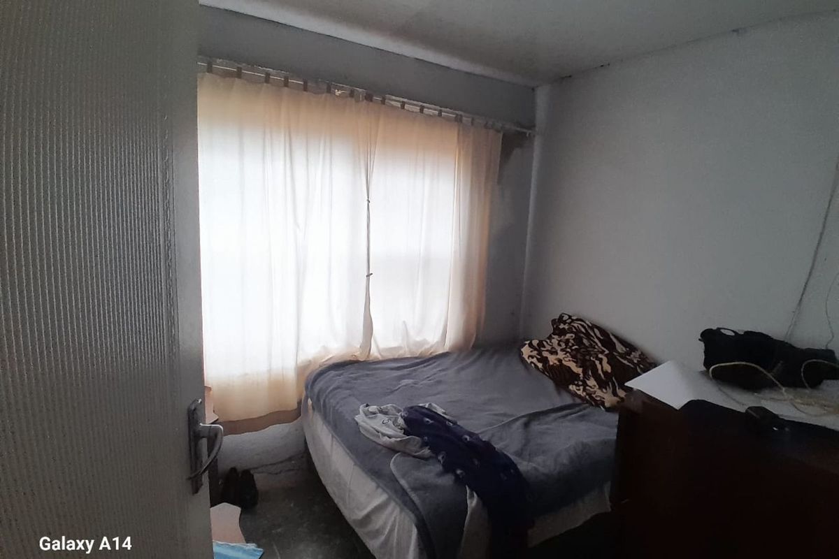 A compact bedroom featuring tiled flooring and a window with curtain track, requiring cosmetic updates to improve the overall finish.