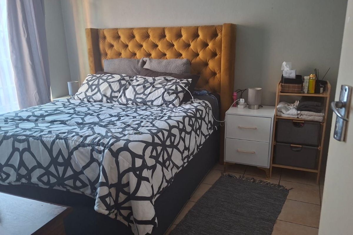 A bedroom featuring tiled flooring and a window with curtains, providing a functional and comfortable living space.