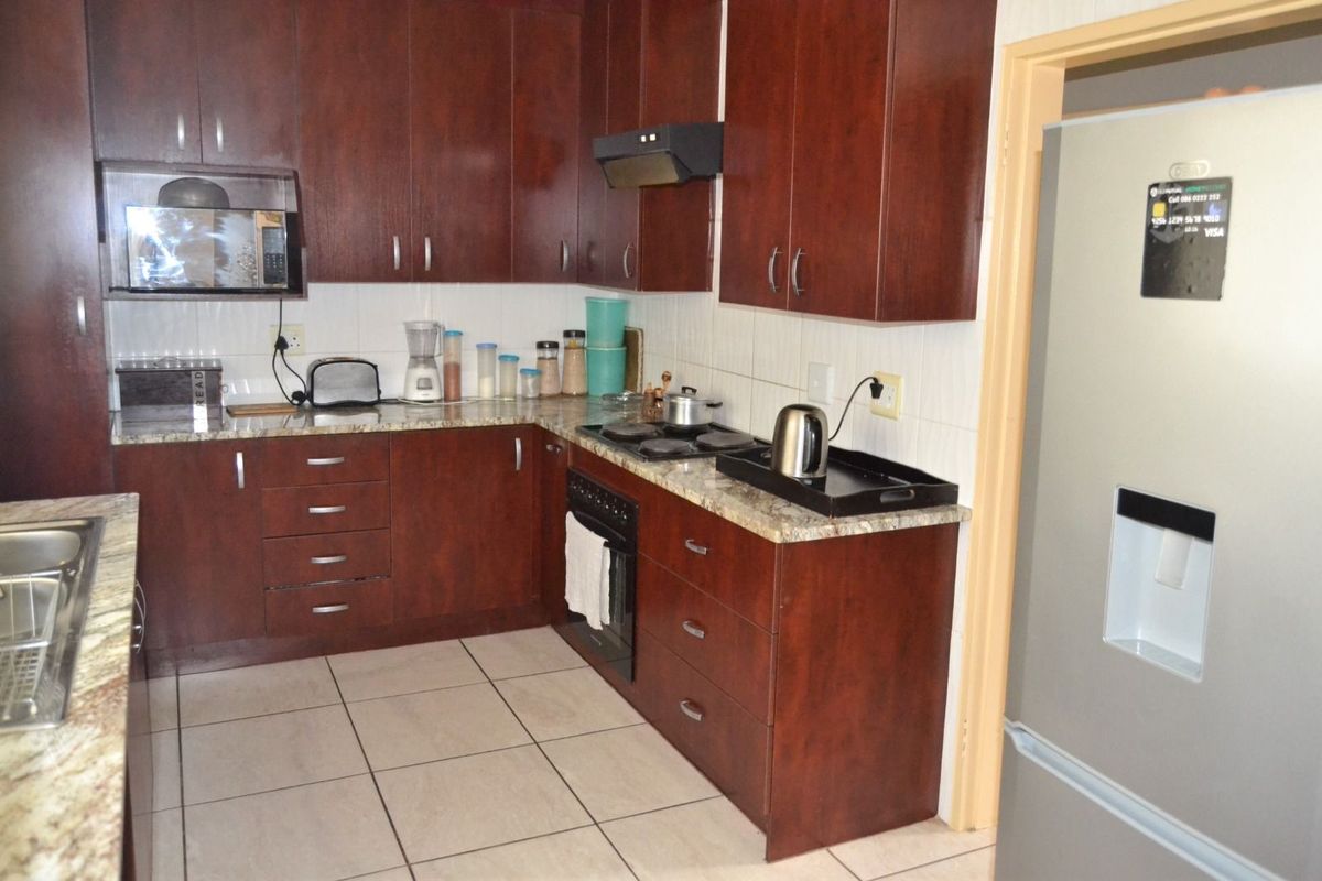 A functional kitchen featuring dark wood cabinetry, granite countertops, tiled backsplash, and built-in oven with extractor fan.