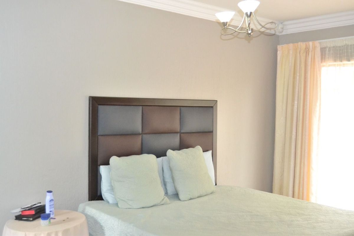 A bedroom featuring crown molding and a window with curtains.