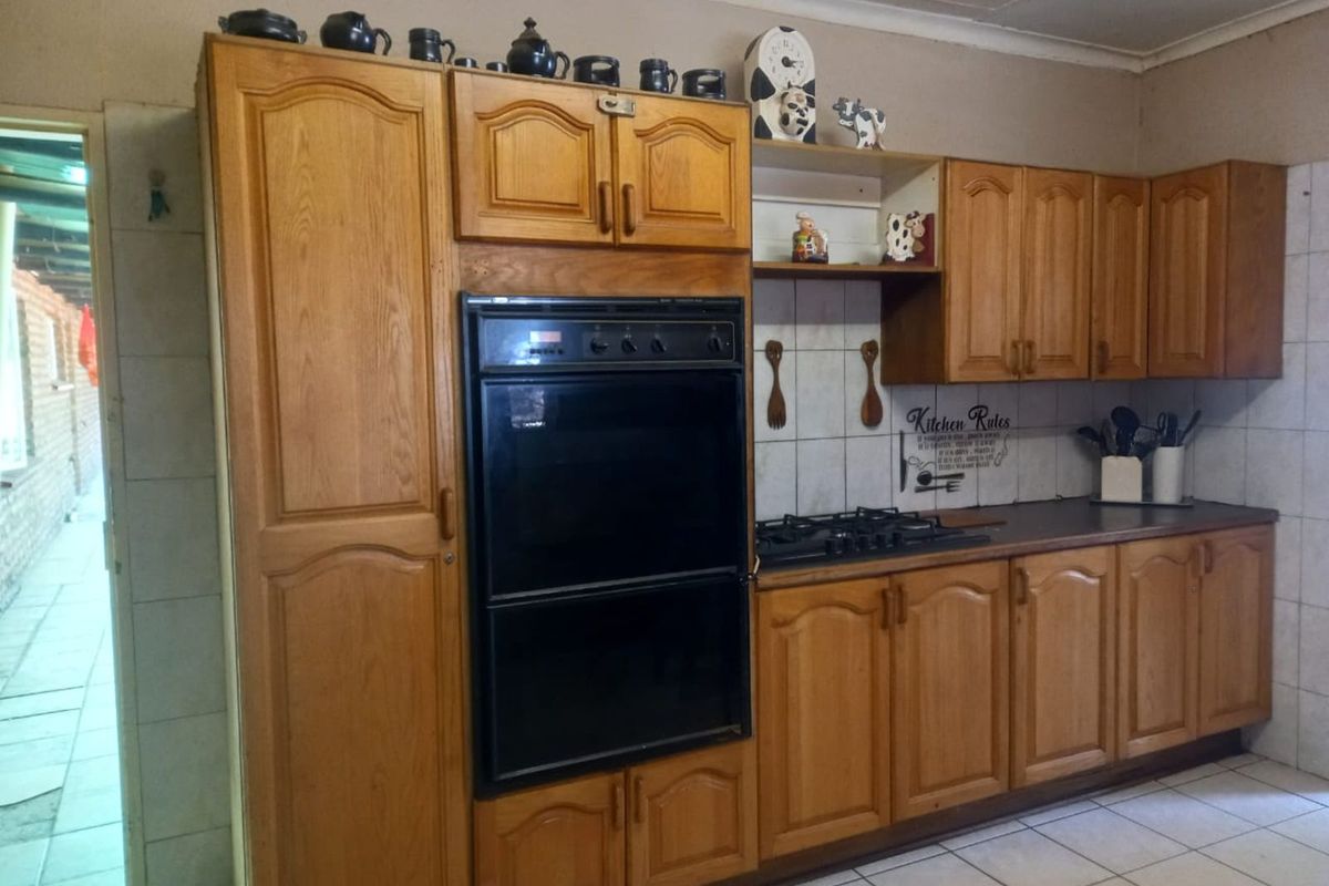 A functional kitchen featuring traditional oak-style cabinetry, a built-in double oven, gas cooktop, and tiled flooring.