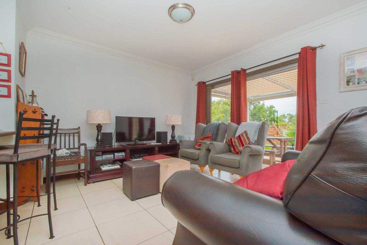 A comfortable living room featuring tiled flooring and large sliding glass doors that provide direct access to the outdoor patio area.