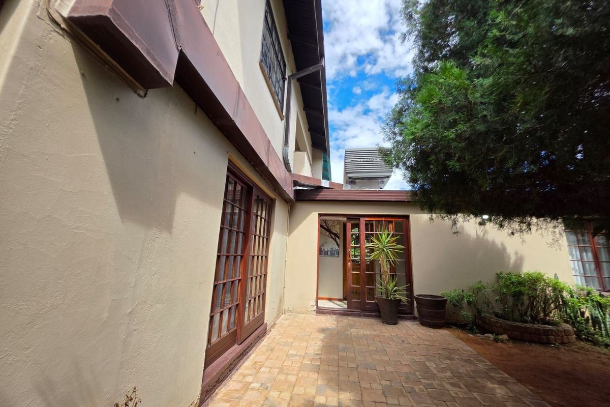 A paved rear patio area featuring timber-framed sliding doors, providing access to the home's interior and adjacent garden space.