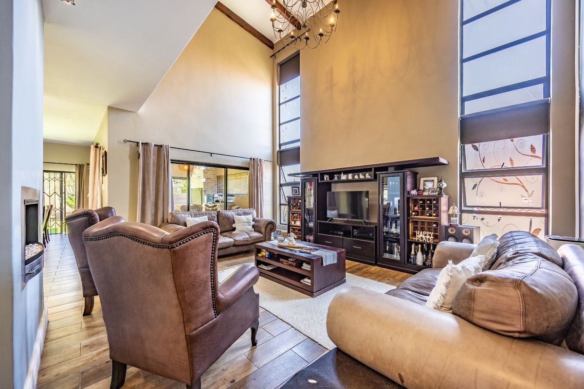 Spacious living room featuring high vaulted ceilings, large windows, wood-look flooring, and a built-in fireplace, creating a bright and airy atmosphere.
