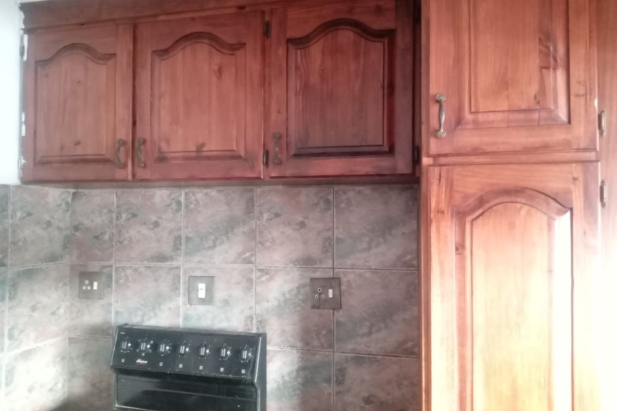A kitchen area featuring traditional wooden cabinetry, a tiled backsplash, and a built-in stove unit.
