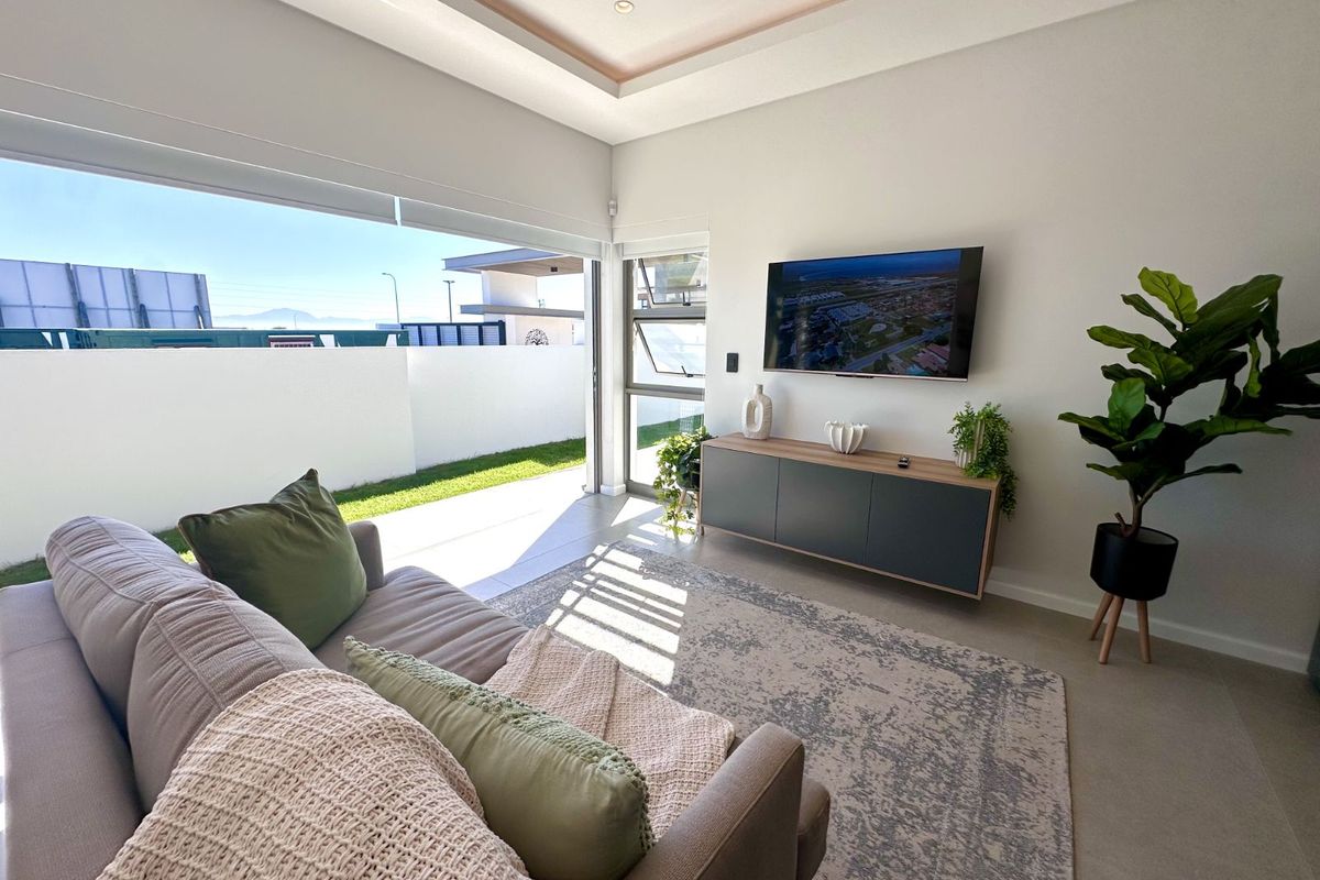 Modern living room featuring a recessed tray ceiling, large sliding glass doors opening to a private patio, and neutral tiled flooring.