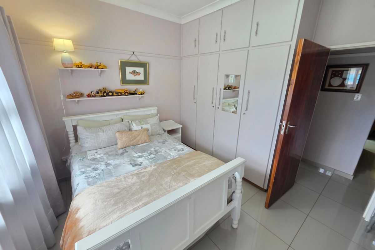 A well-maintained bedroom featuring built-in floor-to-ceiling cabinetry, tiled flooring, and a neutral color palette.