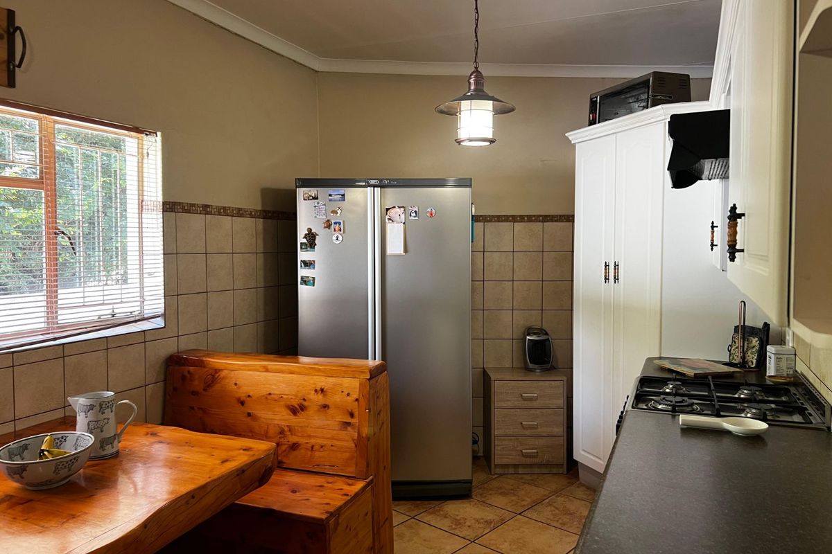 A functional kitchen featuring tiled walls, built-in cabinetry, a gas hob, and a dedicated dining nook with a window view.