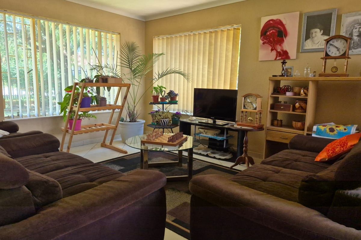 A comfortable living room featuring large windows with vertical blinds, providing ample natural light and a neutral color palette.