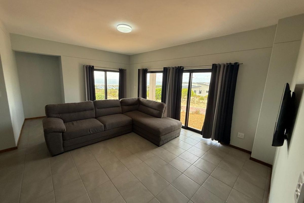 Spacious living room featuring large sliding glass doors that provide natural light and access to the exterior, finished with neutral floor tiles.