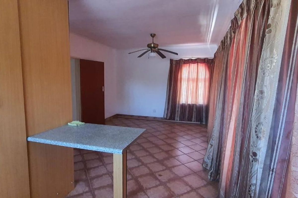 A living area featuring tiled flooring, a ceiling fan, and built-in cabinetry with a breakfast counter.
