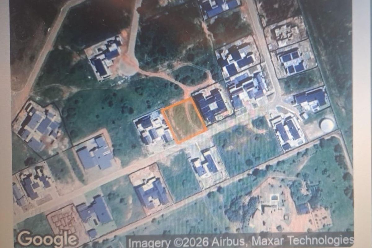Aerial view of a vacant residential plot highlighted within a developed neighborhood, showing surrounding infrastructure and access roads.