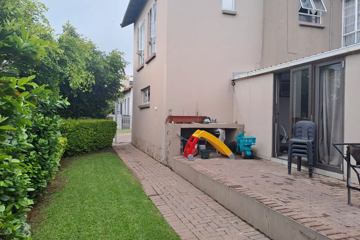 Rear exterior view featuring a paved patio area, small garden space, and access to the home through sliding glass doors.