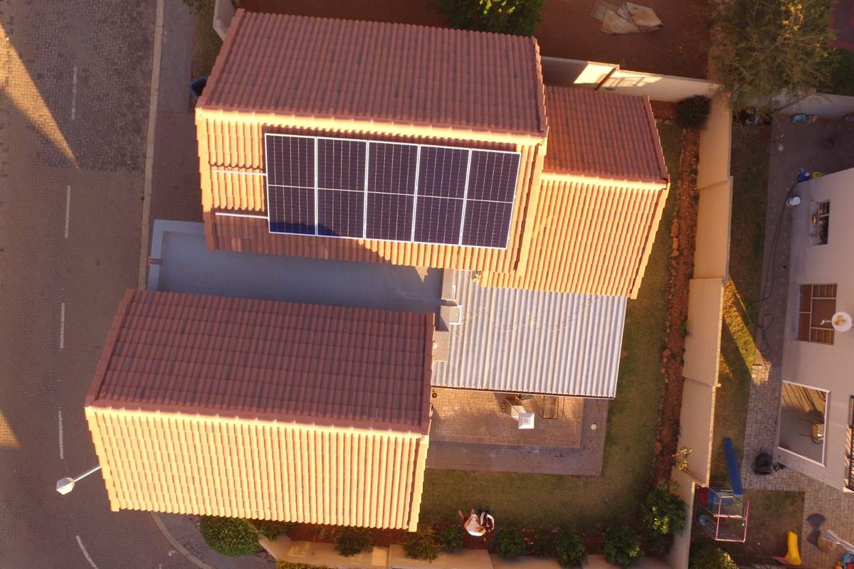 Aerial view of the property showing the tiled roof, installed solar panels, and the surrounding garden and driveway area.