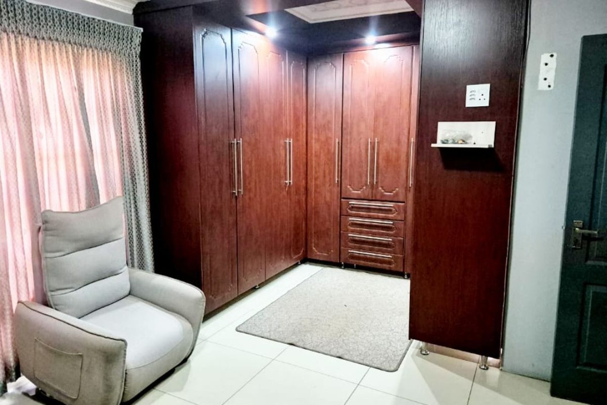 A bedroom featuring extensive built-in dark wood cabinetry with integrated storage and drawers, complemented by tiled flooring and recessed ceiling lighting.
