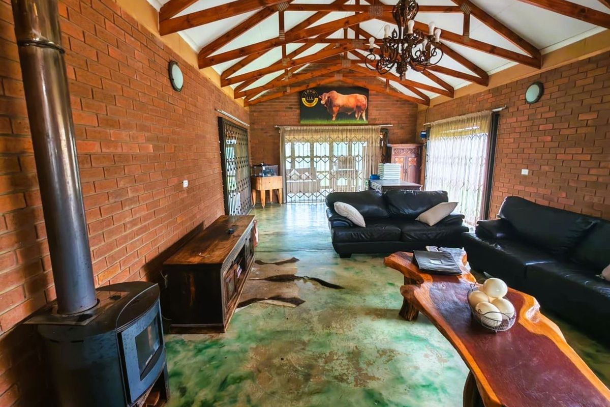 Spacious living area featuring exposed brick walls, high vaulted timber beam ceilings, and a built-in wood-burning fireplace.