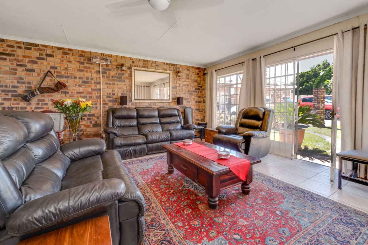 A comfortable living room featuring an exposed brick feature wall, tiled flooring, and large sliding glass doors providing direct access to the outdoor area.