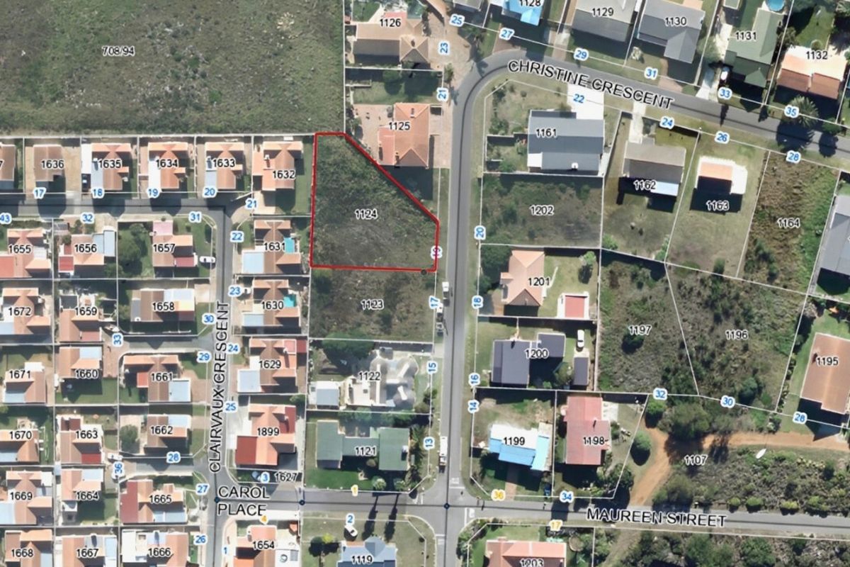 An aerial view showing a vacant residential plot highlighted in red within a suburban neighborhood setting.
