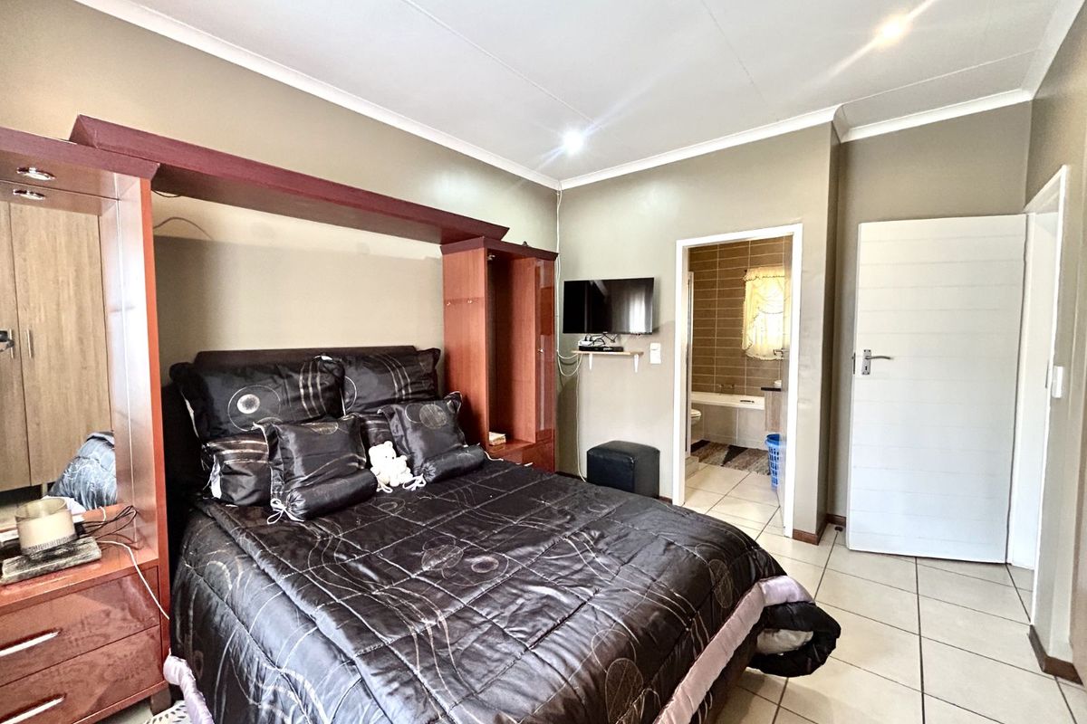 A bedroom featuring built-in wooden cabinetry and an en-suite bathroom with tiled flooring throughout.