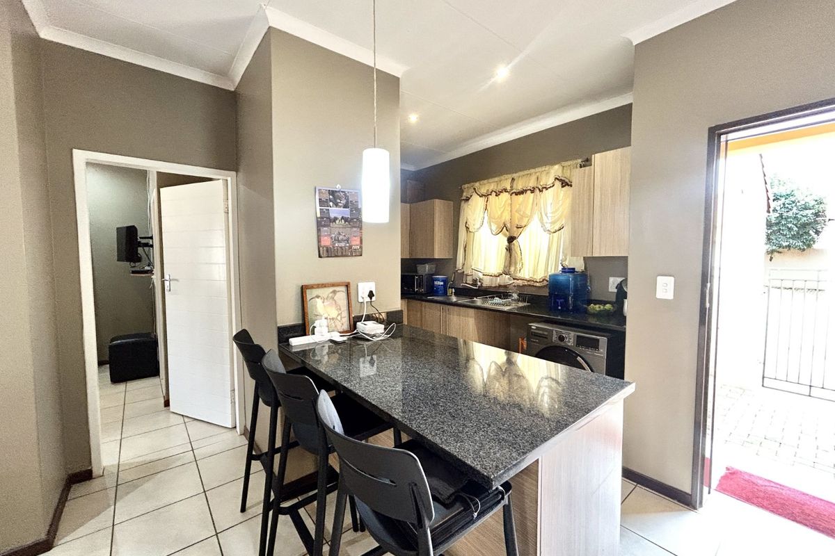 A functional kitchen featuring a granite-topped breakfast bar, built-in cabinetry, and tiled flooring with direct access to an outdoor area.