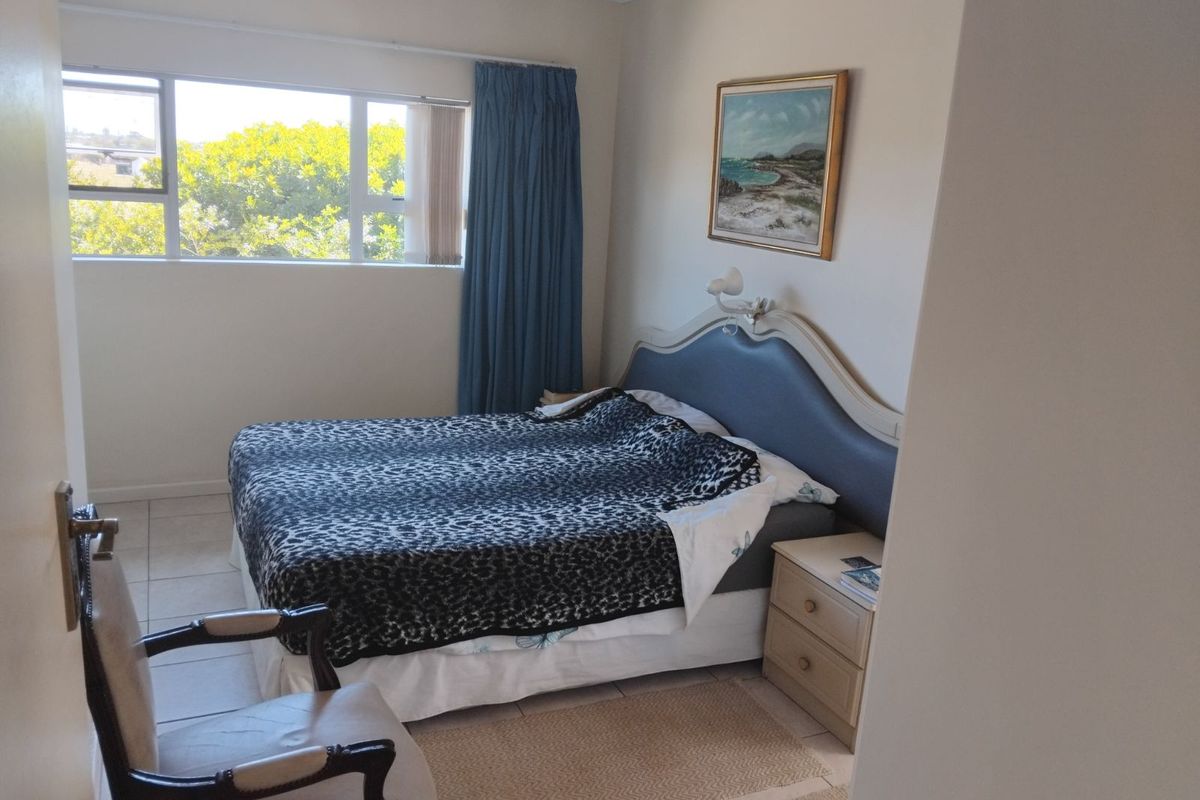 A bedroom featuring tiled flooring, a large window with natural light, and neutral wall finishes.