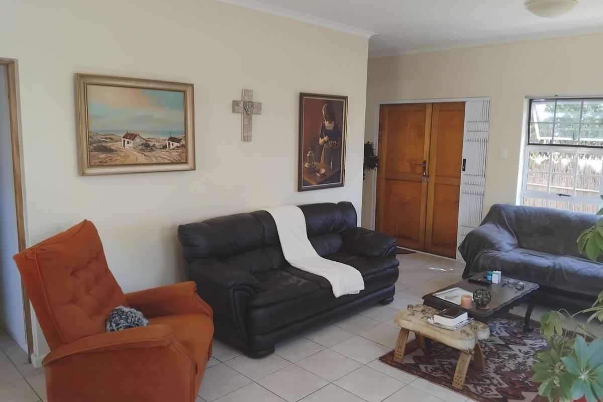 A living room featuring neutral walls, tiled flooring, and a wooden entrance door with security gate.