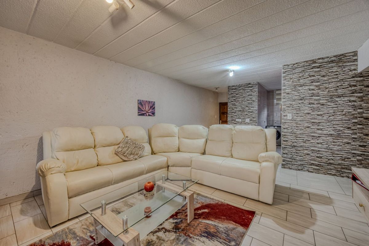 A living room featuring textured wall finishes and a decorative stone-cladding feature wall, complemented by neutral floor tiling.