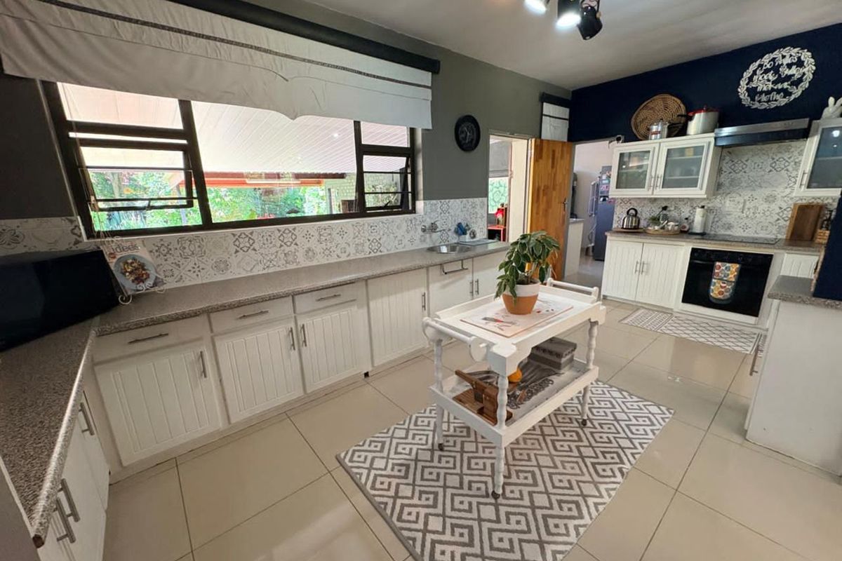 A well-maintained kitchen featuring white cabinetry, patterned tile backsplash, stone-look countertops, and integrated oven with extractor fan.