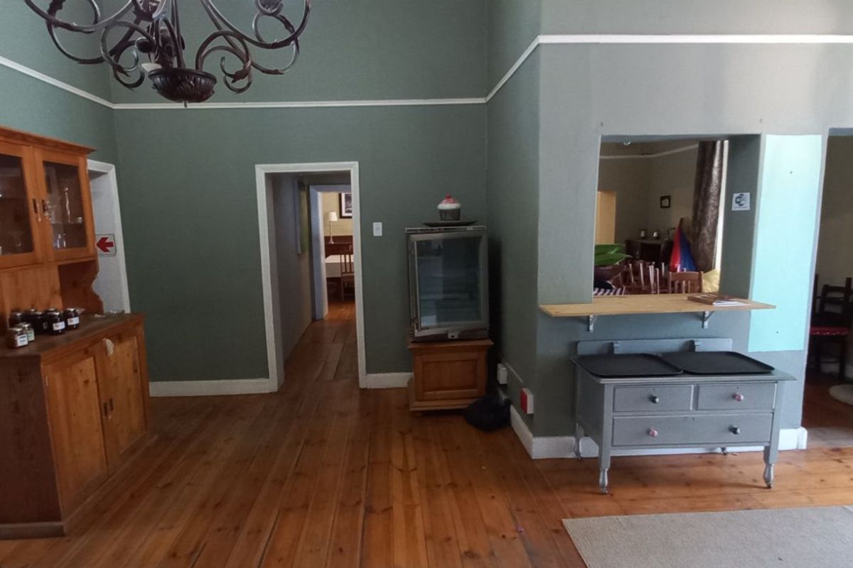 A spacious interior area featuring high ceilings, polished wooden flooring, and a serving hatch connecting to an adjacent room.