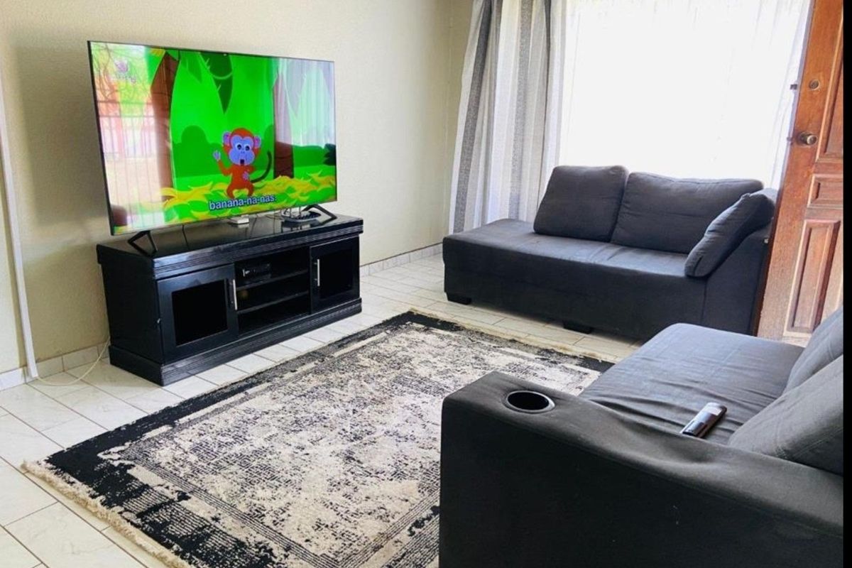 A living room featuring tiled flooring and a large window with curtains, providing a functional and comfortable space for relaxation.