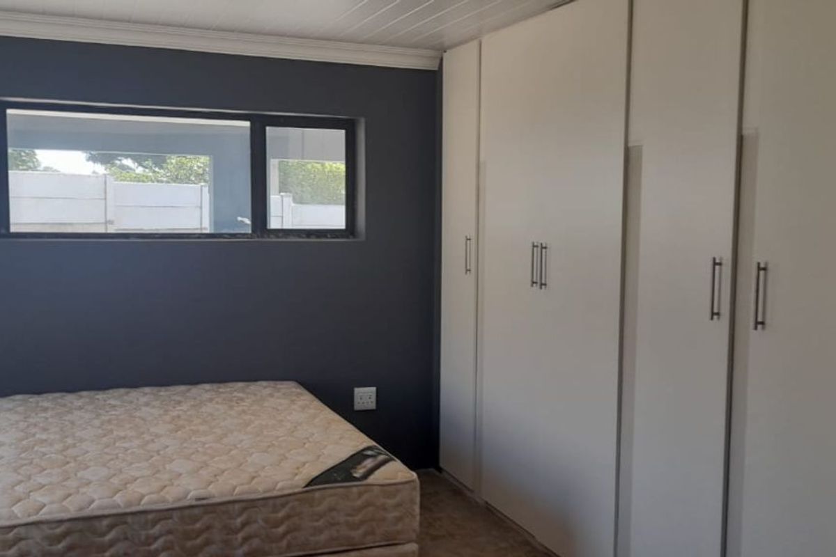 Bedroom featuring dark grey walls, built-in white cabinetry, and a horizontal window providing natural light.