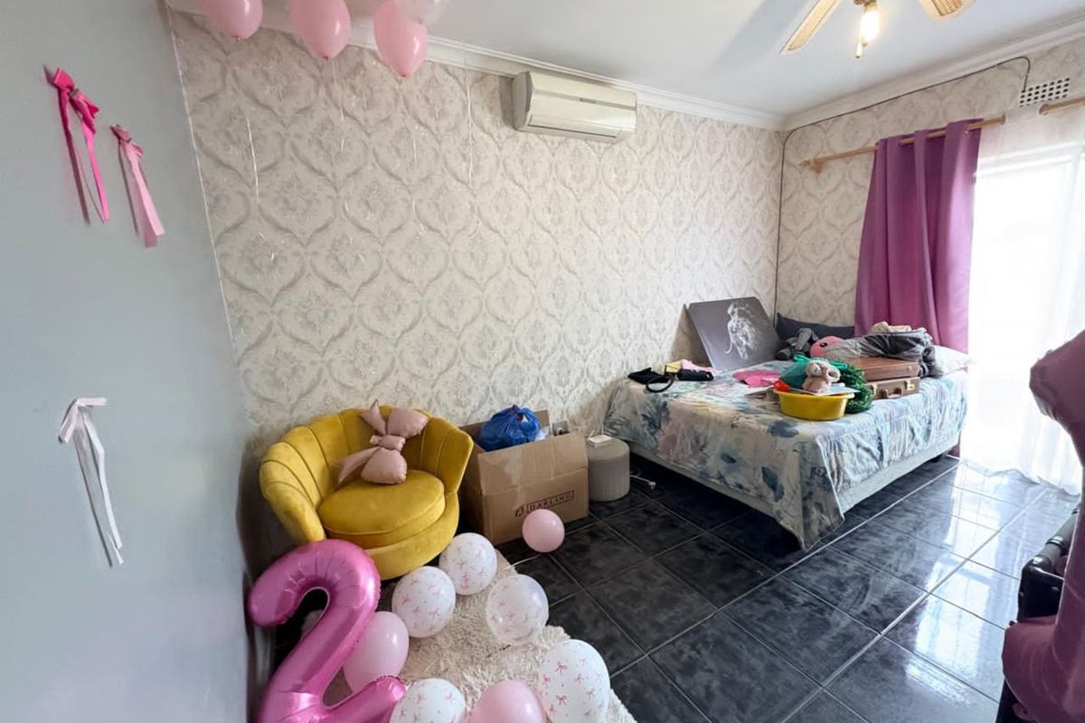 A bedroom featuring tiled flooring, a wall-mounted air conditioning unit, and patterned wallpaper, offering a functional space with potential for modernization.