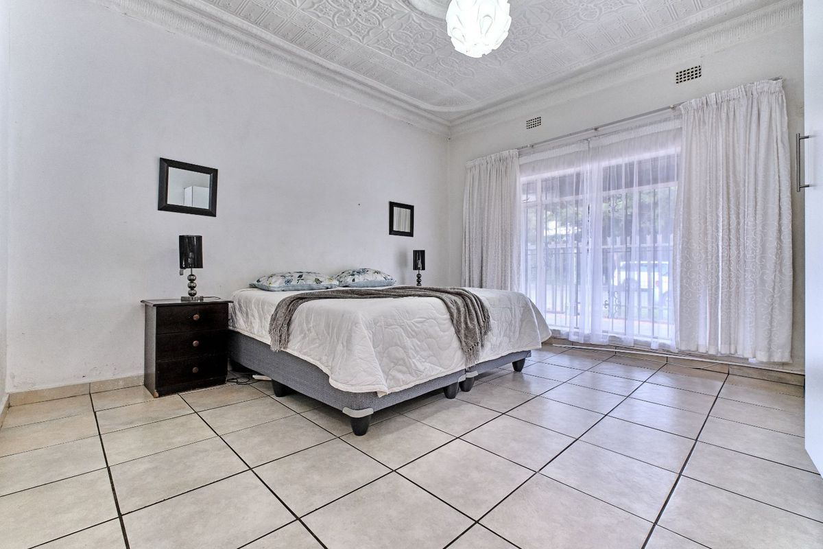 Spacious bedroom featuring decorative pressed ceilings, tiled flooring, and large sliding glass doors providing direct access to the exterior.