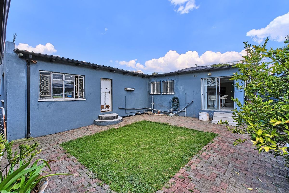 Rear view of the property featuring a paved courtyard, small lawn area, and direct access to the interior via sliding glass doors.