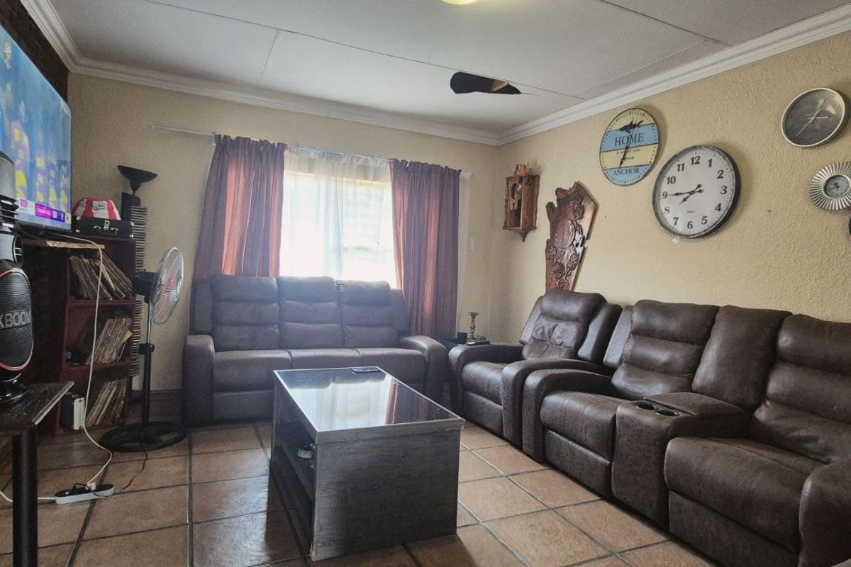A living room featuring tiled flooring, a brick accent wall, and a ceiling fan, providing a comfortable space for relaxation.