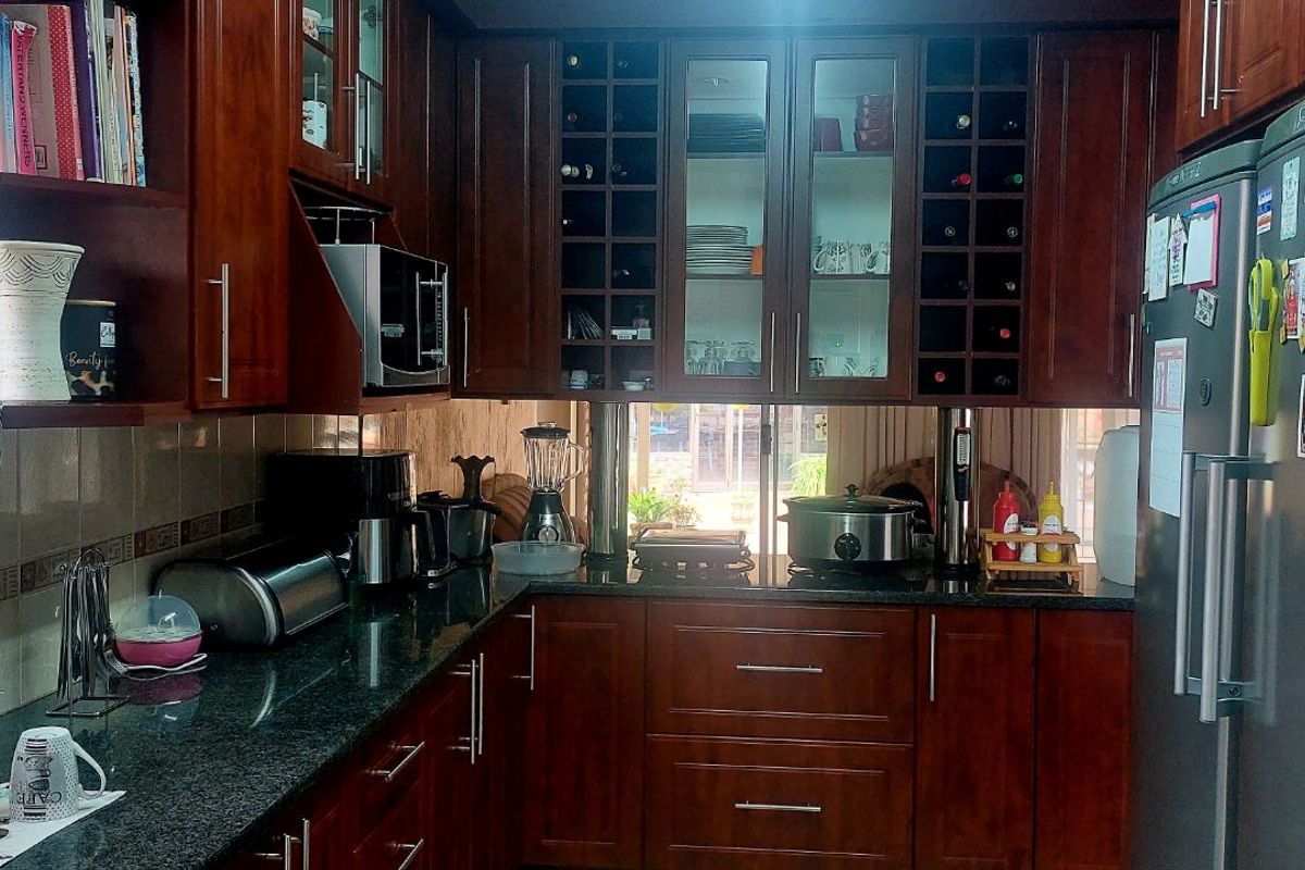 A functional kitchen featuring dark wood cabinetry, granite countertops, and built-in wine storage, offering ample storage and workspace for daily meal preparation.
