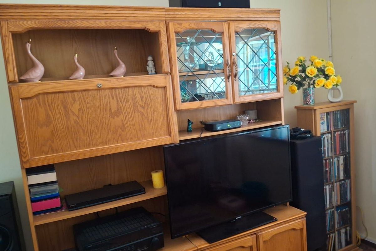 A living room area featuring a large, built-in wooden wall unit with glass-paneled cabinetry and integrated shelving.