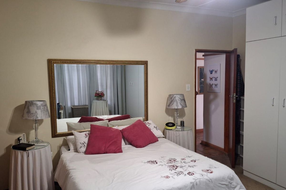 A bedroom featuring built-in cupboards and a doorway leading to an adjacent space.