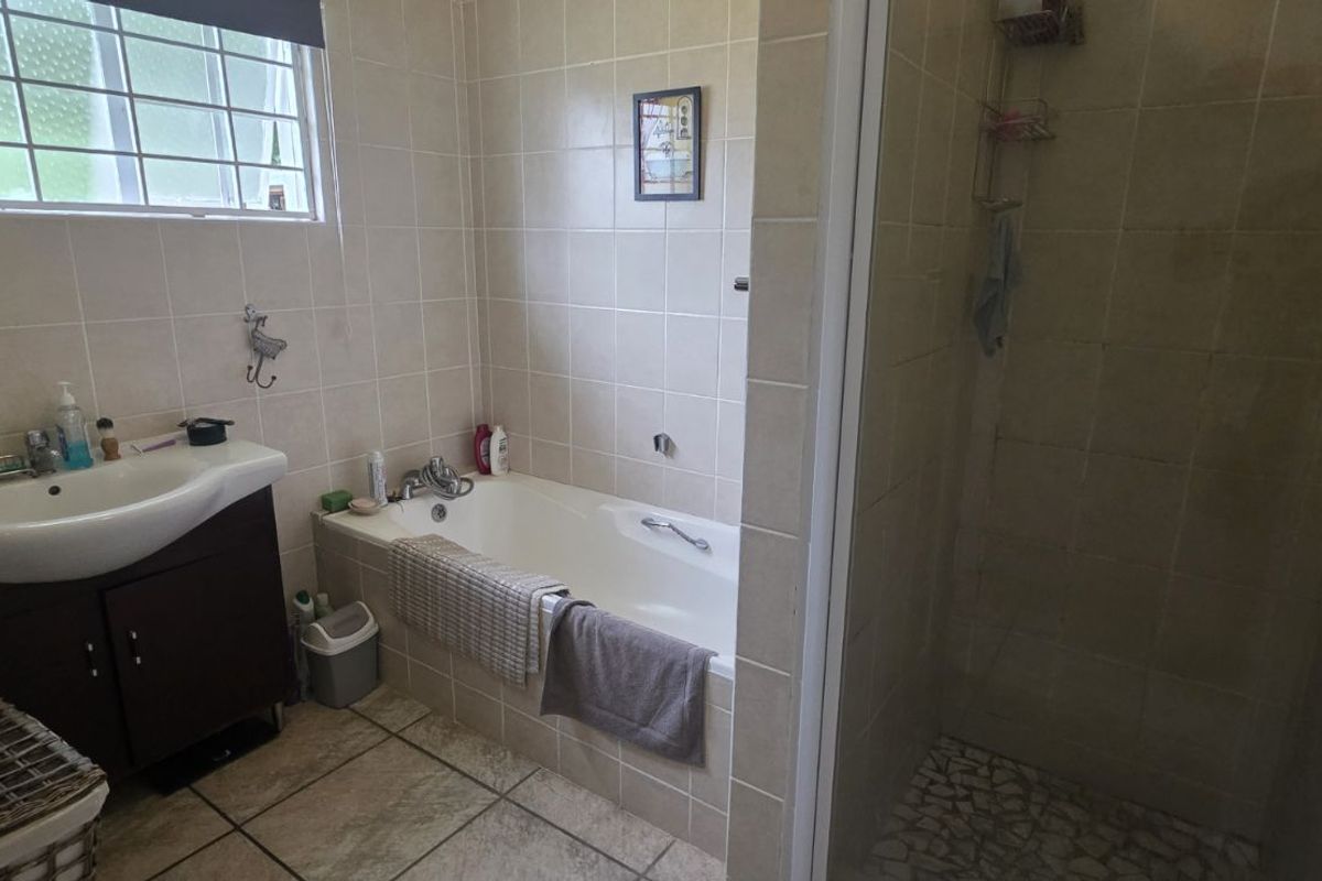A functional bathroom featuring a built-in bathtub, separate shower enclosure, and a vanity basin with storage cabinetry.