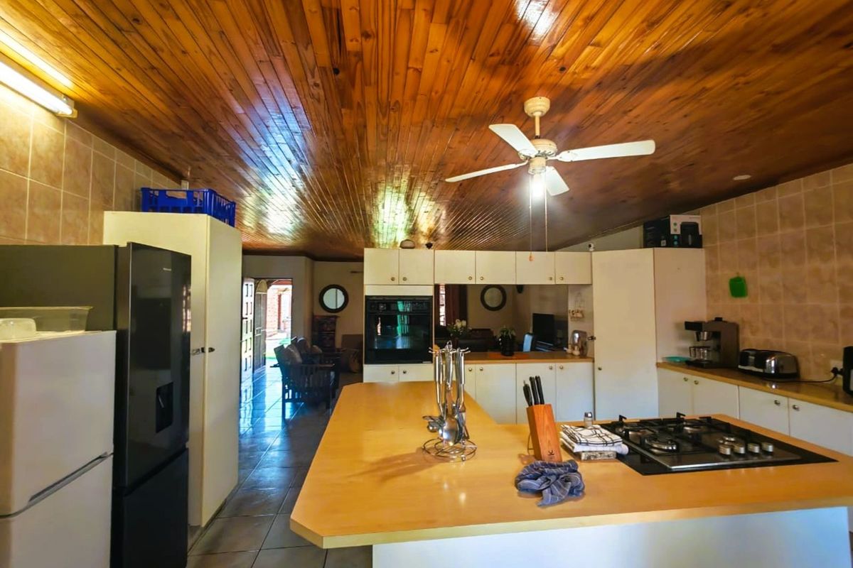 Spacious kitchen featuring a central island with built-in gas hob, integrated oven, and extensive cabinetry, opening into an adjacent living area.