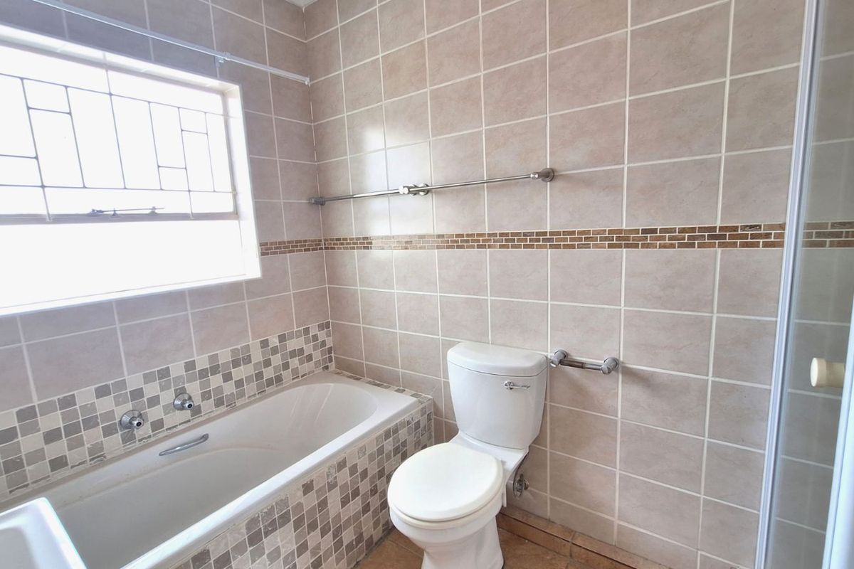A functional bathroom featuring a built-in bathtub, a standard toilet, and tiled wall finishes with a decorative mosaic border.