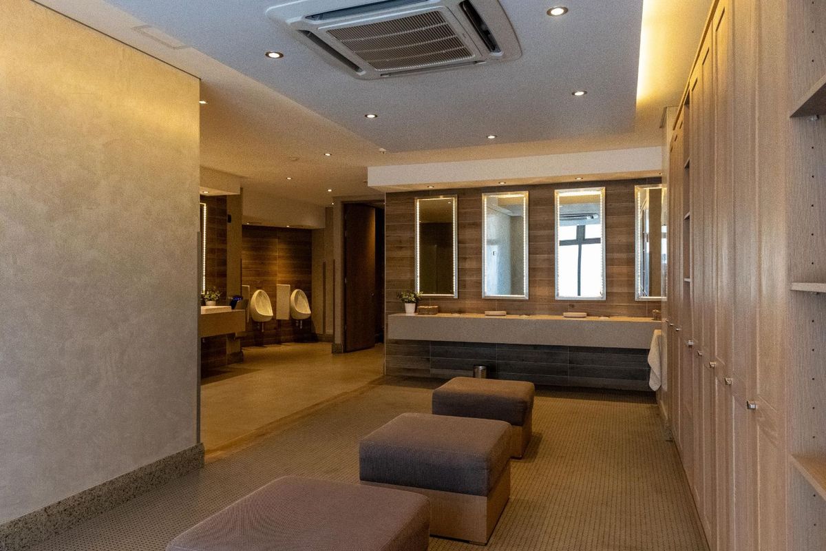 Modern office restroom facility featuring integrated vanity mirrors, wall-mounted urinals, recessed ceiling lighting, and built-in cabinetry with a clean, contemporary aesthetic.
